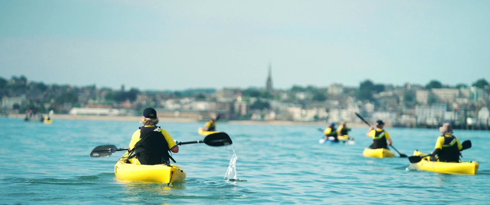 Kayakers in yellow paddling out across the water for Sophie's Legacy